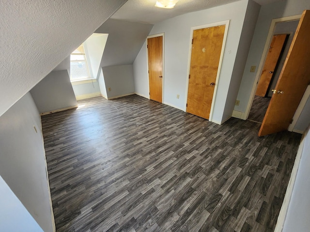 bonus room featuring a textured ceiling, dark wood-type flooring, and vaulted ceiling