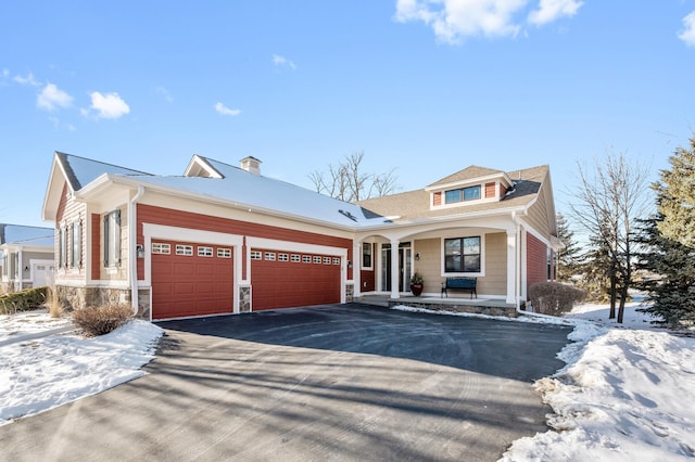 view of front facade featuring stone siding, covered porch, driveway, and an attached garage