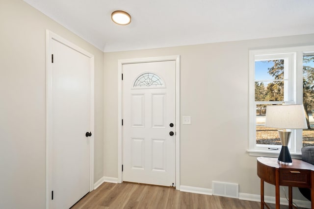 foyer entrance with light wood finished floors, visible vents, and baseboards