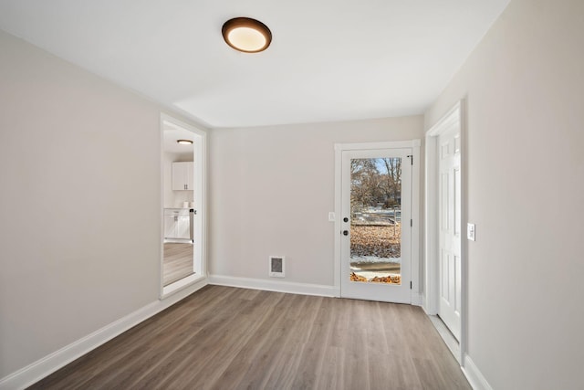 spare room featuring visible vents, baseboards, and wood finished floors