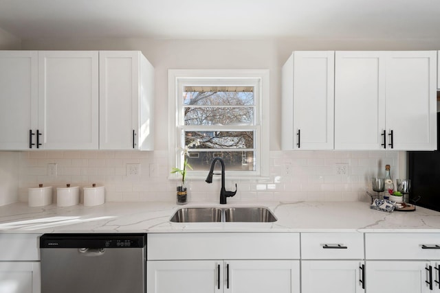 kitchen with light stone counters, a sink, white cabinetry, stainless steel dishwasher, and tasteful backsplash