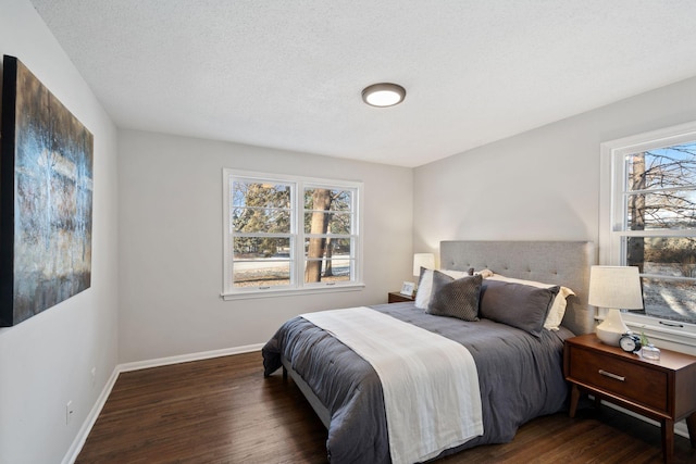 bedroom featuring a textured ceiling, baseboards, and dark wood-type flooring