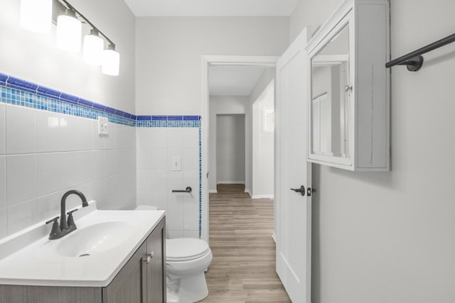 bathroom featuring toilet, tile walls, hardwood / wood-style floors, and vanity