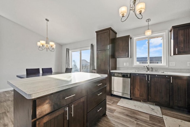 kitchen with a center island, dark brown cabinetry, sink, stainless steel dishwasher, and a chandelier