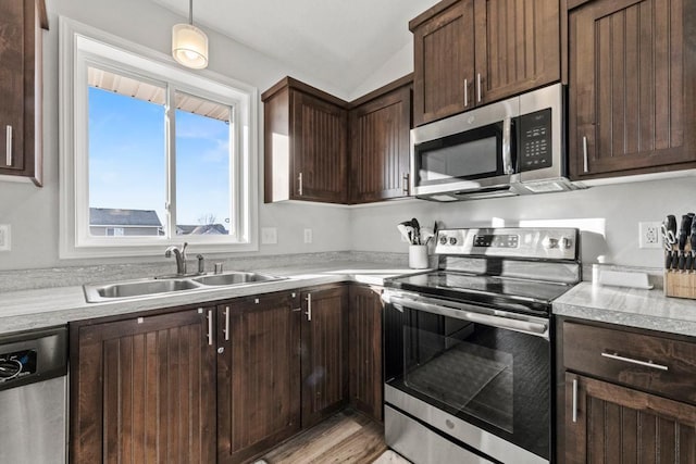 kitchen featuring appliances with stainless steel finishes, sink, vaulted ceiling, pendant lighting, and dark brown cabinetry