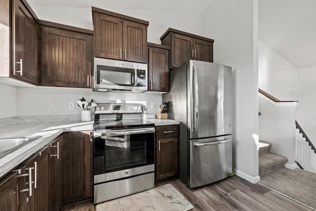 kitchen featuring vaulted ceiling, dark brown cabinets, and stainless steel appliances