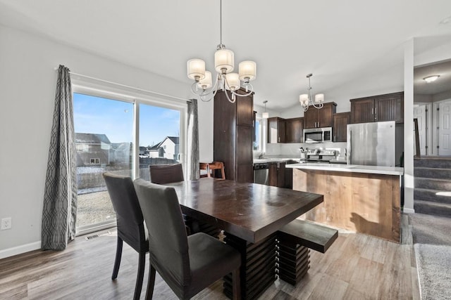 dining area with light hardwood / wood-style floors, an inviting chandelier, and sink