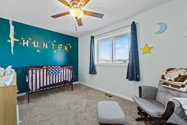 bedroom with a crib, carpet floors, and ceiling fan