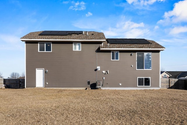 back of house featuring a yard, solar panels, and central air condition unit