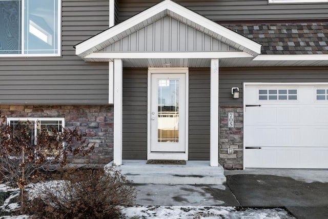 snow covered property entrance with a garage