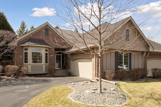 view of front of house featuring an attached garage, aphalt driveway, and brick siding