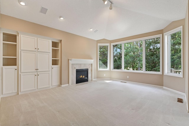 unfurnished living room with carpet flooring, a tile fireplace, baseboards, and visible vents