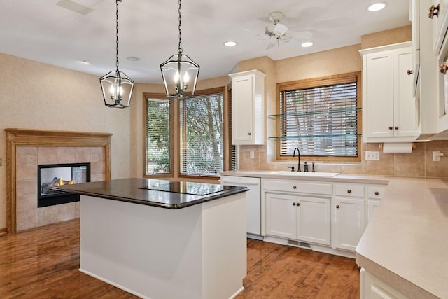 kitchen with a kitchen island, decorative backsplash, white dishwasher, a sink, and wood finished floors