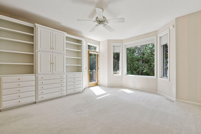 unfurnished bedroom with baseboards, ceiling fan, a textured ceiling, access to exterior, and light carpet