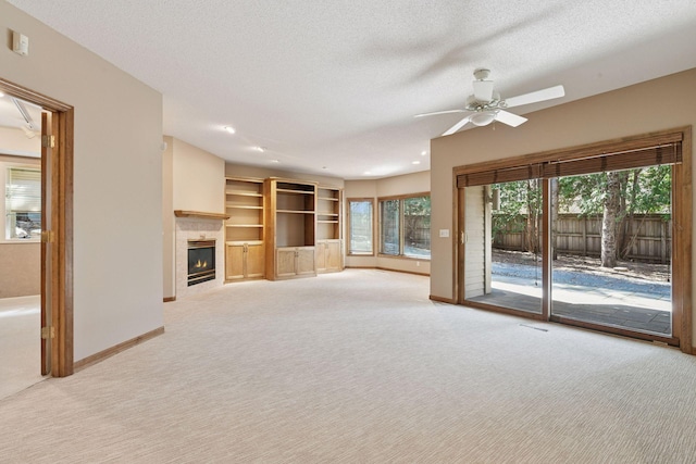 unfurnished living room featuring a tiled fireplace, ceiling fan, baseboards, and carpet