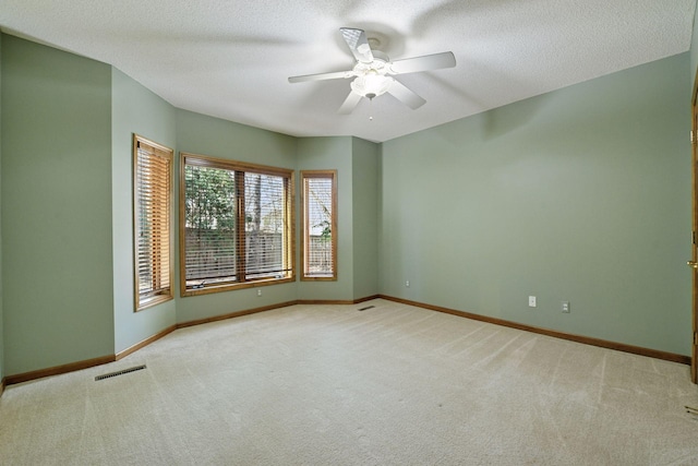empty room featuring carpet flooring, visible vents, baseboards, and a ceiling fan