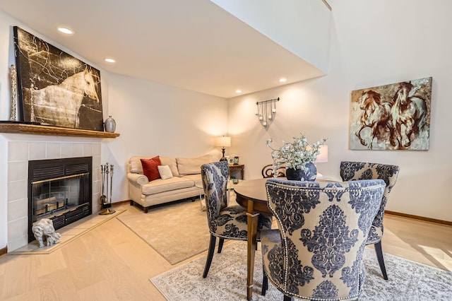 dining area with hardwood / wood-style floors and a tiled fireplace