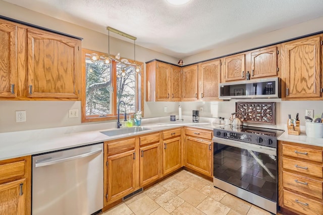 kitchen featuring decorative light fixtures, sink, stainless steel appliances, and a textured ceiling