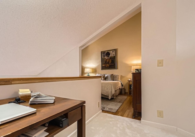 bedroom with a textured ceiling, lofted ceiling, and light wood-type flooring