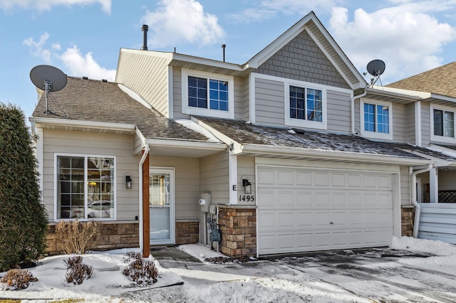 view of property with a garage, stone siding, and roof with shingles