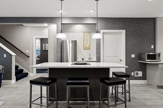 221 George St, Excelsior, MN 55331 - kitchen with appliances with stainless steel finishes, a breakfast bar area, baseboards, a center island, and hanging light fixtures