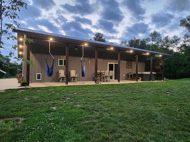 back of property with metal roof, a lawn, and a patio