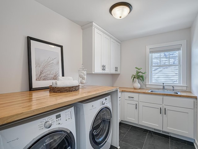 laundry area featuring separate washer and dryer, a sink, and cabinet space