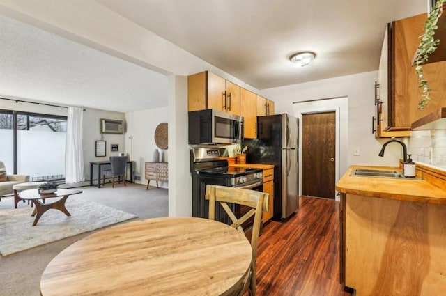 kitchen featuring appliances with stainless steel finishes, open floor plan, brown cabinets, a wall mounted air conditioner, and a sink