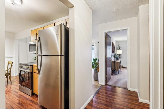 kitchen featuring appliances with stainless steel finishes, dark wood-style flooring, light brown cabinets, and a textured ceiling