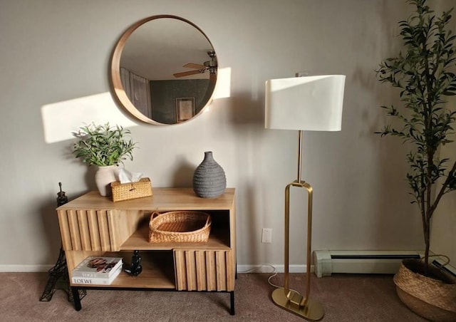 living area with a baseboard heating unit, carpet floors, a ceiling fan, and baseboards