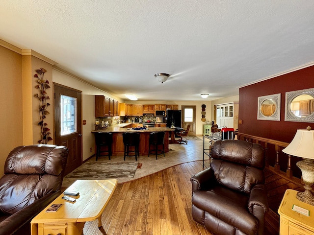 living room with a healthy amount of sunlight, light wood-style floors, crown molding, and a textured ceiling