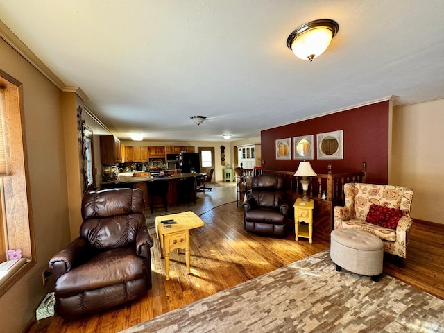 living area with crown molding and light wood-style floors