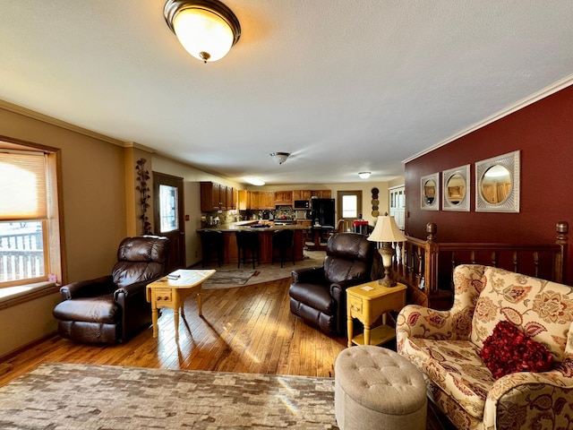 living room with a healthy amount of sunlight, light wood-style flooring, and crown molding