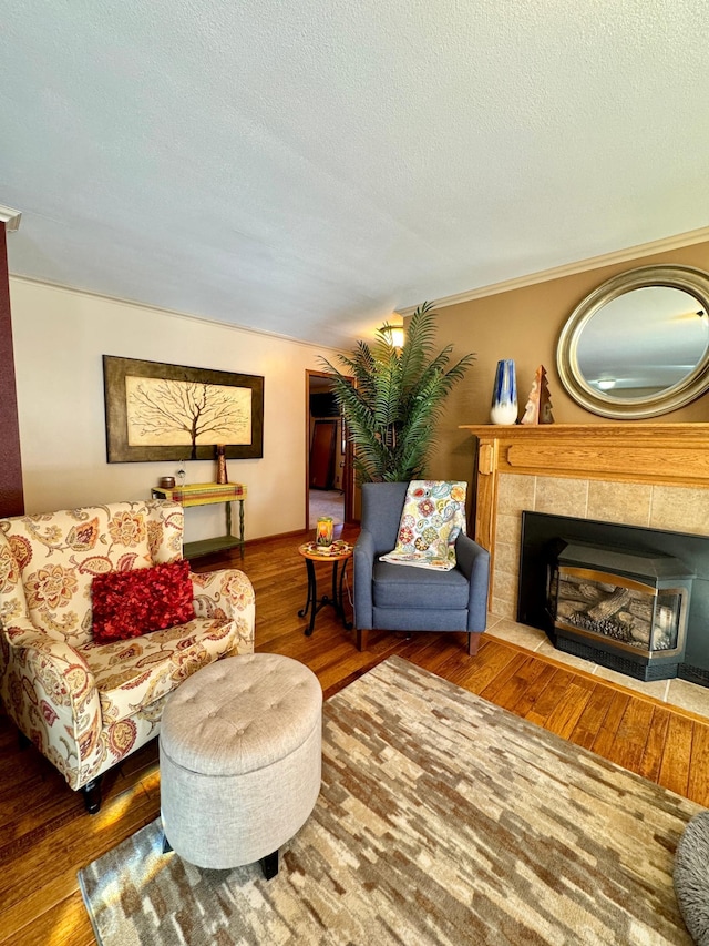 living area with a textured ceiling, dark wood-style flooring, and a tiled fireplace