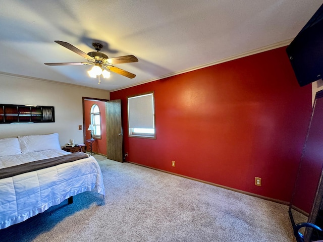 carpeted bedroom with ceiling fan, baseboards, and crown molding