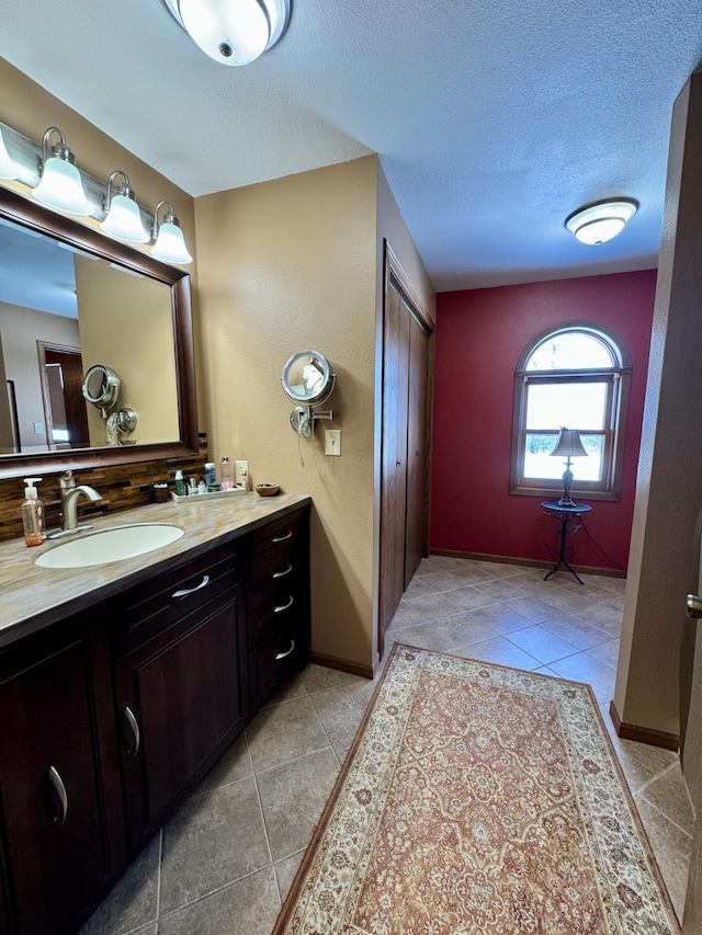 bathroom with tile patterned flooring, baseboards, vanity, and a textured ceiling