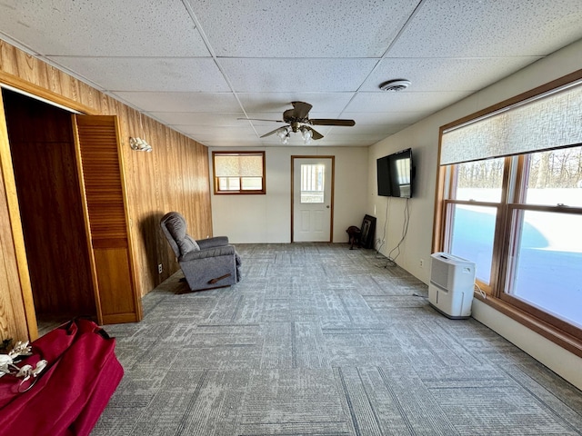 unfurnished room with carpet floors, a paneled ceiling, visible vents, and wooden walls