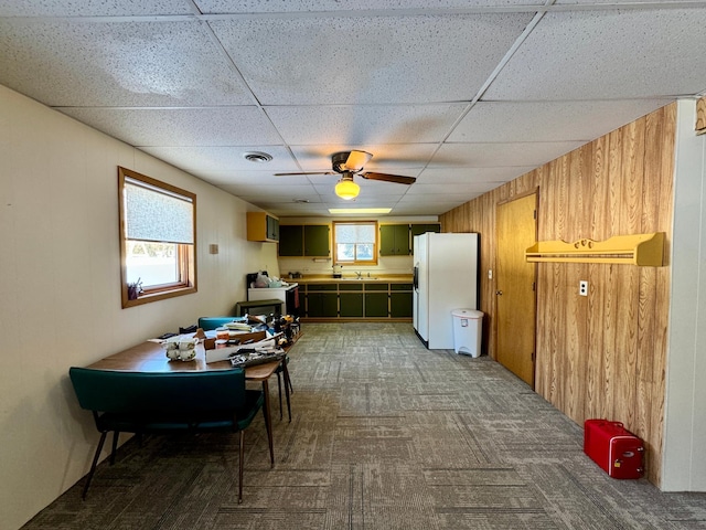 interior space featuring wooden walls, carpet floors, white refrigerator with ice dispenser, visible vents, and green cabinets