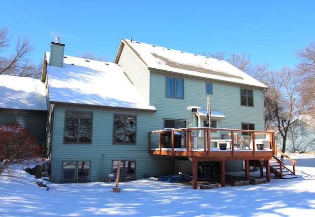 snow covered house featuring a wooden deck