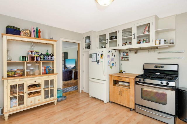 kitchen with stainless steel gas range oven, light wood-style floors, freestanding refrigerator, open shelves, and glass insert cabinets