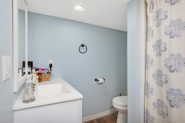 bathroom with baseboards, vanity, toilet, and wood finished floors