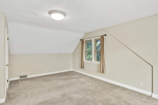 bonus room with light carpet, baseboards, visible vents, lofted ceiling, and a textured ceiling