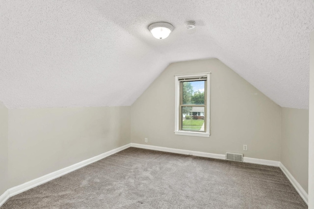 additional living space with carpet, visible vents, lofted ceiling, and baseboards