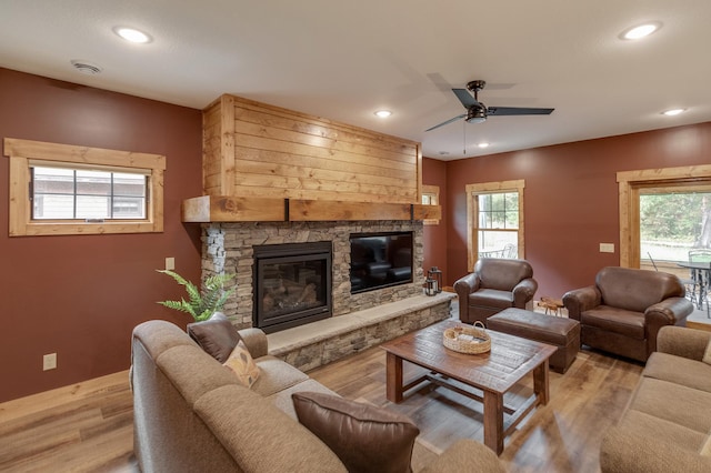 living room featuring a ceiling fan, recessed lighting, a fireplace, and light wood finished floors