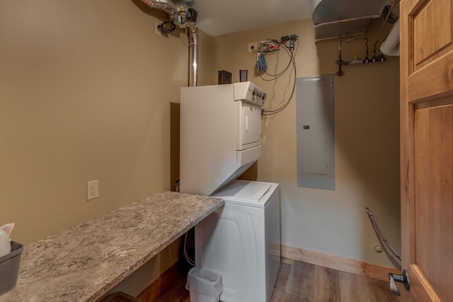 laundry room featuring laundry area, stacked washer and dryer, dark wood-style flooring, baseboards, and electric panel