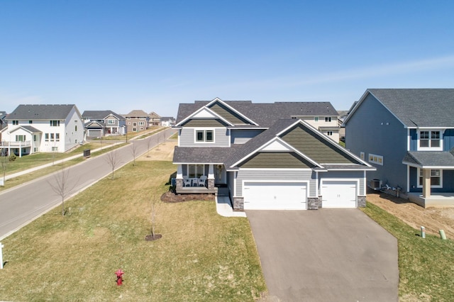 craftsman-style home with a front yard, fence, a residential view, stone siding, and driveway