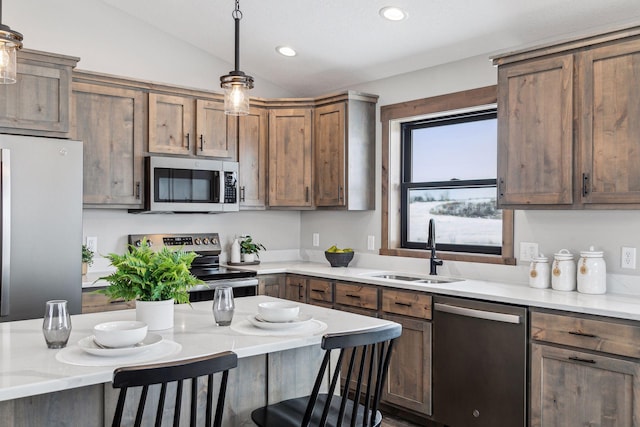 kitchen featuring appliances with stainless steel finishes, sink, vaulted ceiling, a breakfast bar, and hanging light fixtures