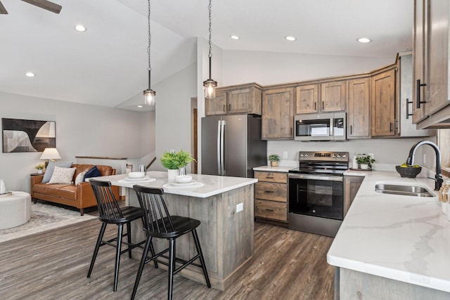 kitchen featuring dark wood-type flooring, stainless steel appliances, decorative light fixtures, a kitchen island, and sink