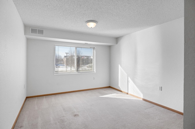 carpeted empty room featuring a textured ceiling