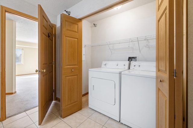 clothes washing area with light tile patterned floors, separate washer and dryer, and a textured ceiling